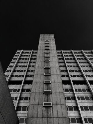 The same tower in deep shadow, its windows catching what light there is, against a black sky.
